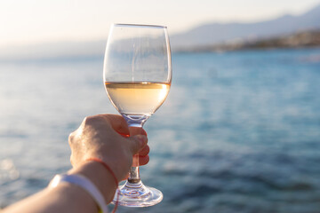 Wine in hands of woman against sea background. Selective focus.