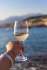 Wine in hands of woman against sea background. Selective focus.