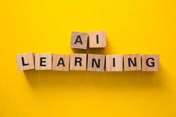Wooden cubes showing ai learning on yellow background
