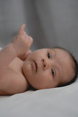 Curious Newborn Looking Up While Lying on Bed Portrait of an alert newborn baby with expressive...