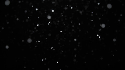 Sparkling droplets suspended in air create mesmerizing effect against dark background, evoking sense of wonder and tranquility