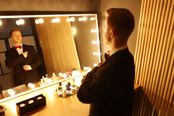 Handsome man getting ready near dressing table indoors
