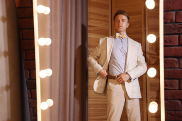 Handsome man getting ready near mirror indoors