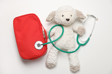 Pediatrics concept. Toy sheep with stethoscope and first aid kit on white background, top view