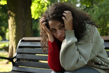 Poor homeless woman on bench in park, space for text