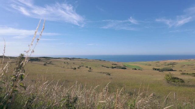 Cap Blanc-Nez, Escalles, Pas-de-Calais, Hauts-de-France, France, July 29th, 2025, Experience a breathtaking view of a coastal landscape with rolling hills, golden grass, and a clear blue sky
