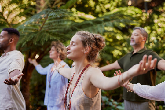 Young woman meditating with a group of diverse people outdoor