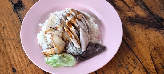 Chicken rice on a pink plate on a wooden table