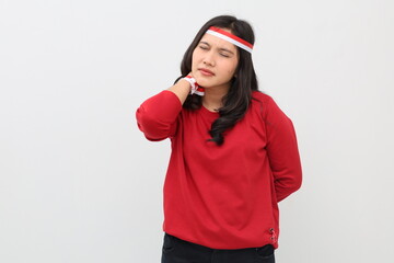 Asian woman with red and white ribbon on head, celebrating Indonesian independence day, standing holding neck, sore or tired, neck pain, isolated on white background.