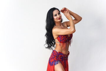 Brunette Red Dress Performing Eastern Dance Movements Against a White Background.