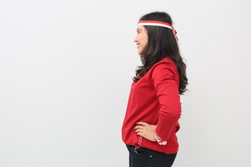 Side view of Indonesian woman with red and white ribbon celebrating Indonesian independence day with hands on waist, isolated on white background with copy space on the side.