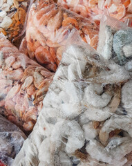 Raw frozen shrimp in a transparent plastic bag for vacuum packaging. Selective focus