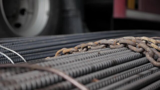 Close-up of steel rebar and chains on a construction site. Industrial materials are stacked together, showcasing the texture and details of the metal.