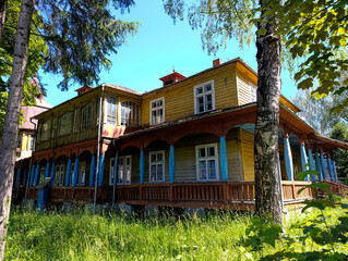 A yellow house in the middle of a grassy field surrounded by trees