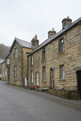 Eyam, The Peak District, England - January 21 2025: Charming stone cottages row on overcast winter day in Eyam, the Peak District, England.