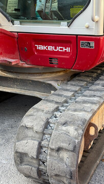 Malaga, Spain - July 25, 2025: Takeuchi excavator with visible tracks and red body parked on construction site showcasing heavy machinery details