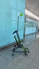 Barcelona, Spain - July 15, 2025: Airport luggage cart with green sign indicating gate 114, positioned on polished floor near glass walls