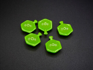 Close-up of green hair vitamin capsules on a dark background. The shiny softgel pods are shaped...