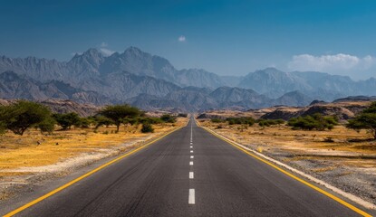 Fototapeta premium Empty highway stretches into a mountain range under a clear sky