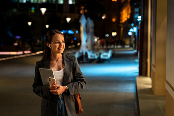 Smiling urban woman window shopping at night in fashion district
