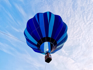 Colorful blue hot air balloon rising into the sky during a summer festival. Clear blue sky.  View...