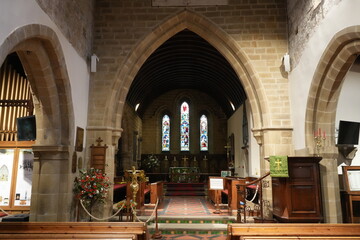 Eyam, The Peak District, England – January 21 2025: Stone arch interior with stained glass...