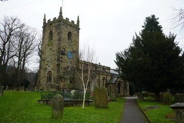 Fototapeta premium Eyam, The Peak District, England – January 21 2025: Stone church and graveyard in the winter light