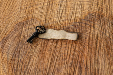 An antique key resting on a burnt piece of paper placed on a rustic wooden block, evoking a mysterious message from the past.
