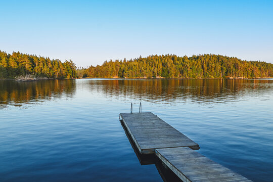 Steg am ruhigen See mit Insel und Spiegelung &ndash; Badeplatz in schwedischer Natur