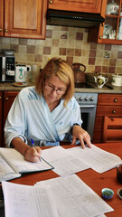 Woman in bathrobe managing household finances at kitchen table