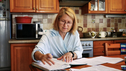 Older Woman Reviewing Finances at Kitchen Table