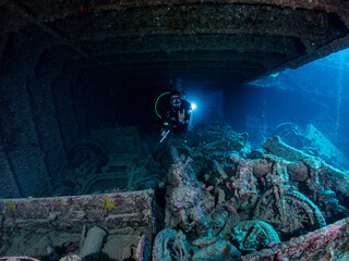 Scuba diver explores a sunken ship, SS Thistlegorm, filled with fish in total underwater silence in...