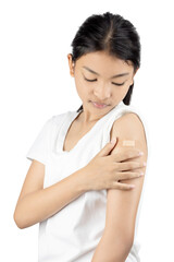 Asian girl looking at the bandage on her arm after vaccination. A thoughtful and contemplative moment reflecting the reality of immunization.
