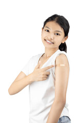 Happy smiling Asian girl points to a bandage on her arm after a Covid-19 vaccine. Successful immunization concept isolated on white background with clipping path.