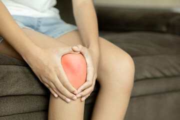 Woman with knee pain holding an aching joint with a red highlight for inflammation. Arthritis, injury, or muscle ache concept.