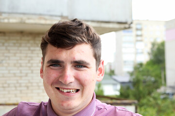 A young Caucasian man in his 20s, 18-29 years old, with a genuine smile revealing slightly crooked teeth, walks outside in nature. authentic expression, despite subtle acne