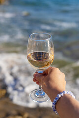 Wine in hands of woman against sea background. Selective focus.