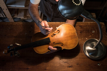 Luthier adjusting the sound post of a violin in his workshop