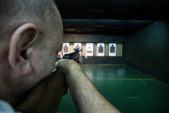 Man aiming with a carbine in an indoor shooting range