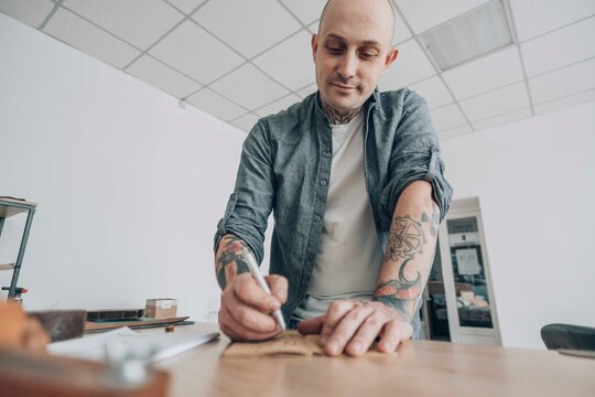 Smiling bald businessman writing with pen on leather patch