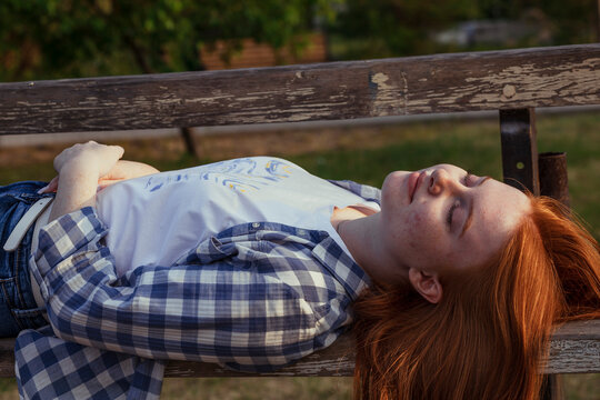 Carefree girl sleeping on bench at public park