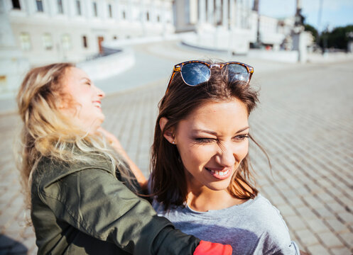 Austria, Vienna, two young women having fun in front of the parliament building