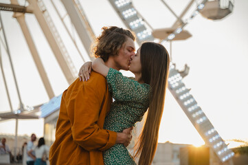 Girlfriend and boyfriend kissing at sunset in amusement park