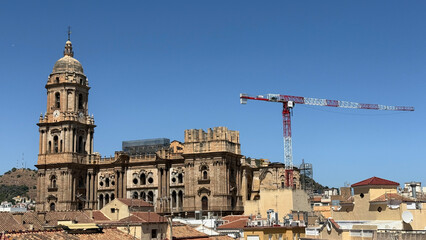Malaga, Spain - July 28, 2025: Malaga Cathedral with construction crane in the background showcasing stunning architecture and vibrant blue sky