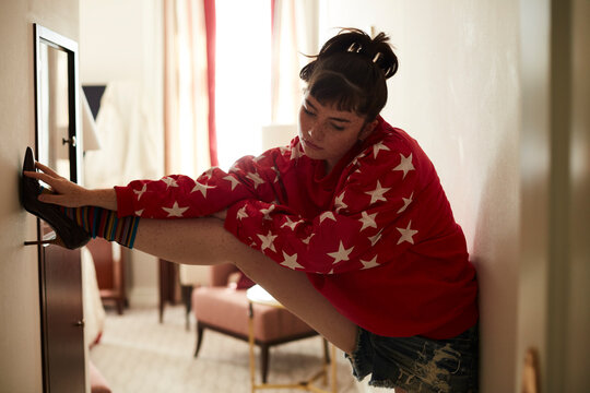 Teenage girl in high heels leaning against a wall