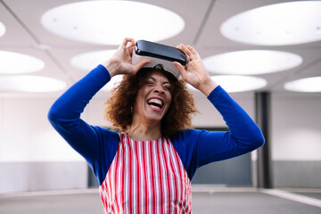 Happy woman with virtual reality simulator standing in parking garage