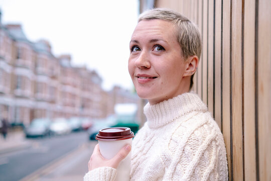 Contemplative woman with reusable cup by wall
