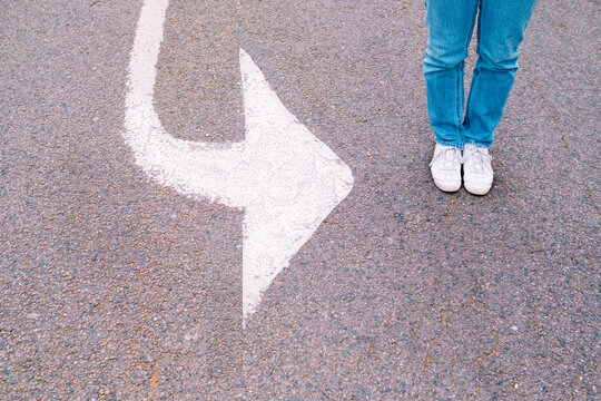 Woman standing by arrow symbol on road