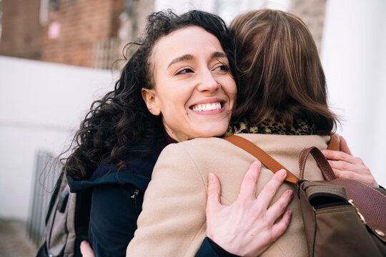 Happy niece embracing aunt outside building
