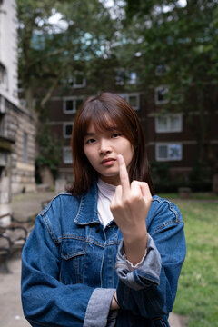 Young woman showing obscene gesture in front of building